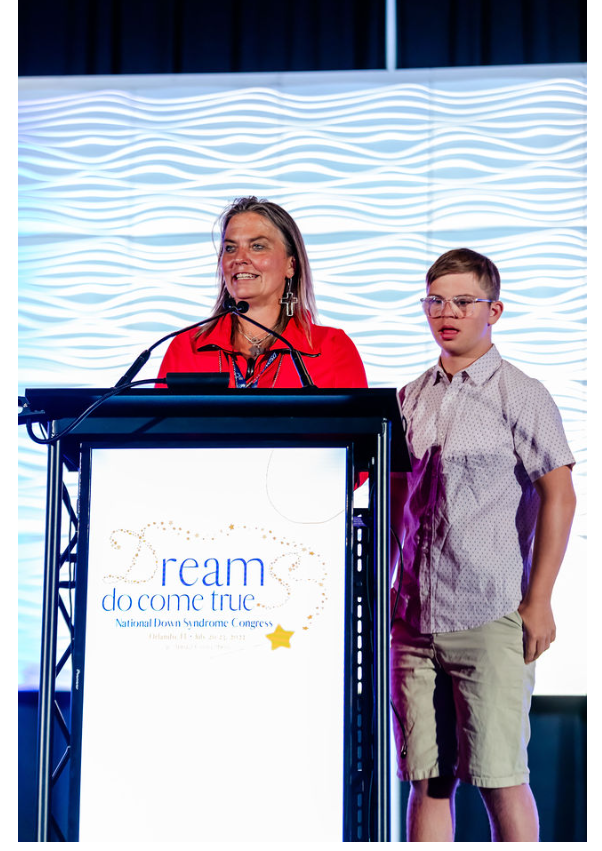 woman in red standing at podium with young man 